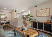 Thumbnail 11 of 13 - A modern living room with a grey sofa, wooden coffee table, and a large abstract art piece on the wall.