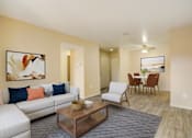 Thumbnail 8 of 13 - A living room with a white couch and a coffee table.