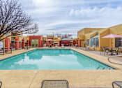 Thumbnail 2 of 13 - A large outdoor swimming pool surrounded by lounge chairs and umbrellas.