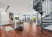 Thumbnail 8 of 51 - Living room with a spiral staircase and a kitchen with a sink and a counter at Equinox, Seattle, WA, 98102