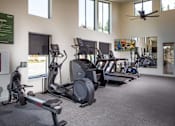 Thumbnail 23 of 34 - A gym with a variety of exercise equipment including treadmills, elliptical machines, and a rowing machine.