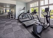 Thumbnail 15 of 23 - A gym with treadmills, elliptical machines, and other exercise equipment.