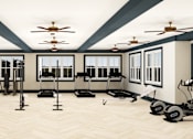 Thumbnail 21 of 26 - A spacious gym with treadmills, elliptical machines, and a fan.