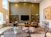 Thumbnail 8 of 26 - A living room with a grey table and a television on the wall.