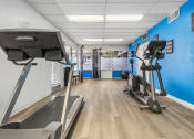 Thumbnail 12 of 23 - a gym with treadmills and other exercise equipment in a building with blue walls