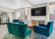 Thumbnail 14 of 23 - Seating area with modern decor, large TV, and natural light.