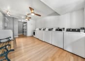 Thumbnail 15 of 23 - Laundry room with washers, dryers, ceiling fans, and wood flooring.