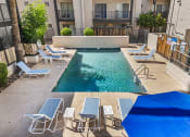 Thumbnail 22 of 23 - a swimming pool with lounge chairs and tables in an apartment building