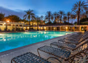 Thumbnail 22 of 28 - a pool with lounge chairs and palm trees in the background