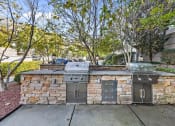 Thumbnail 10 of 21 - a stone barbecue area with two stainless steel appliances on the sidewalk