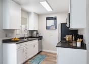 Thumbnail 12 of 15 - a kitchen with white cabinetry and black countertops
