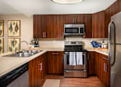 Thumbnail 1 of 27 - Kitchen with stainless steel appliances and wooden cabinets at Ascend2300, Carlsbad, 92008