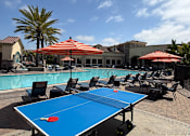 Thumbnail 32 of 33 - A blue table tennis table is in the middle of a poolside area.