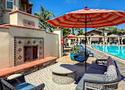 Thumbnail 3 of 33 - A patio with a red umbrella and blue chairs.