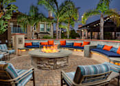 Thumbnail 2 of 33 - A fire pit in the middle of a patio surrounded by chairs and cushions.