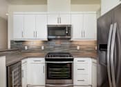 Thumbnail 5 of 33 - A modern kitchen with white cabinets and a stainless steel refrigerator.