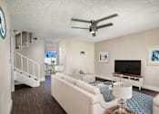 Thumbnail 6 of 22 - A living room with a white couch and a ceiling fan.