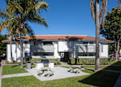 Thumbnail 21 of 22 - A white building with a red roof is surrounded by palm trees.