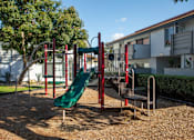 Thumbnail 17 of 22 - A playground with a green slide and red and green equipment.
