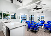 Thumbnail 14 of 22 - A modern kitchen with a white countertop and blue chairs.