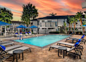 Thumbnail 1 of 22 - A pool surrounded by chairs and umbrellas with a building in the background.
