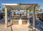 Thumbnail 15 of 22 - A patio with a grill and chairs under a white canopy.