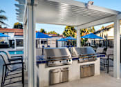 Thumbnail 13 of 22 - A barbecue grill is set up under a white pergola.