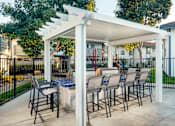 Thumbnail 3 of 22 - A patio with a table and chairs under a white pergola.