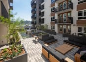Thumbnail 34 of 48 - an image of an apartment patio with wooden furniture and potted plants at VORA LUX, San Diego, CA