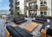 Thumbnail 6 of 48 - a patio with couches and tables in front of an apartment building at VORA LUX, California, 92120