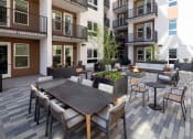 Thumbnail 36 of 48 - an outdoor patio with tables and chairs at the bradley braddock road station apartments at VORA LUX, San Diego, 92120