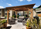 Thumbnail 33 of 33 - A wooden pergola with a patio furniture set underneath it.