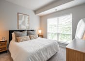 Thumbnail 62 of 68 - A bedroom with a large bed, a nightstand, a lamp, and a window with blinds.