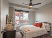 Thumbnail 10 of 34 - A bedroom with a bed, nightstand, and a window overlooking a building.