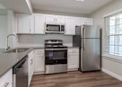 Thumbnail 7 of 19 - an empty kitchen with white cabinets and stainless steel appliances