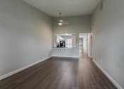 Thumbnail 8 of 19 - an empty living room with hardwood flooring and a hallway to a kitchen