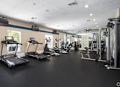 Thumbnail 19 of 24 - A gym with treadmills, exercise bikes, and other equipment.