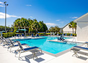 Thumbnail 20 of 24 - A pool with blue water and lounge chairs around it.