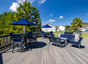 Thumbnail 22 of 24 - A wooden deck with blue chairs and umbrellas.