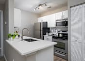 Thumbnail 2 of 24 - A modern kitchen with a white countertop and stainless steel appliances.