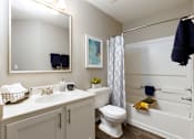 Thumbnail 12 of 24 - A bathroom with a white toilet, sink, and bathtub.