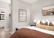 Thumbnail 7 of 37 - A bedroom with a brown comforter and a painting on the wall.