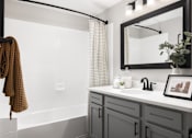 Thumbnail 6 of 37 - A bathroom with a white tub, a sink with a framed picture, and a towel hanging on the railing.