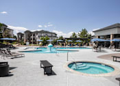 Thumbnail 22 of 37 - A large outdoor swimming pool with a hot tub and lounge chairs.