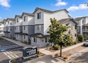 Thumbnail 45 of 46 - A sunny day at the Logger Creek Apartments with clear blue skies and a few cars parked in the lot.