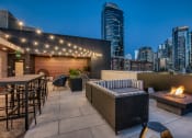 Thumbnail 12 of 30 - a rooftop patio with a city skyline at night