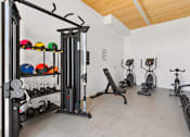 Thumbnail 16 of 22 - A gym with a variety of equipment including weights, a squat rack, and exercise bikes.