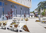 Thumbnail 20 of 22 - A row of white chairs are lined up on a sidewalk.