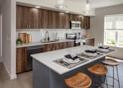 Thumbnail 4 of 34 - A modern kitchen with a large island and wooden stools.