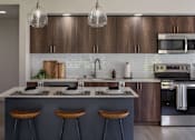 Thumbnail 2 of 34 - A modern kitchen with a bar area and wooden cabinets.